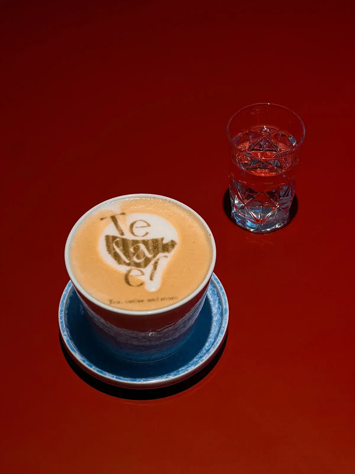 Latte with the Teaffe mark printed on the foam, on a blue saucer